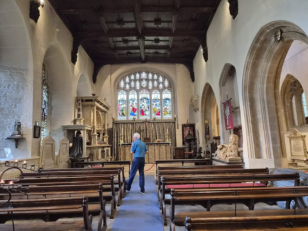 Inside Cirencester church, looking east past the pews to the chancel and its stained-glass east window