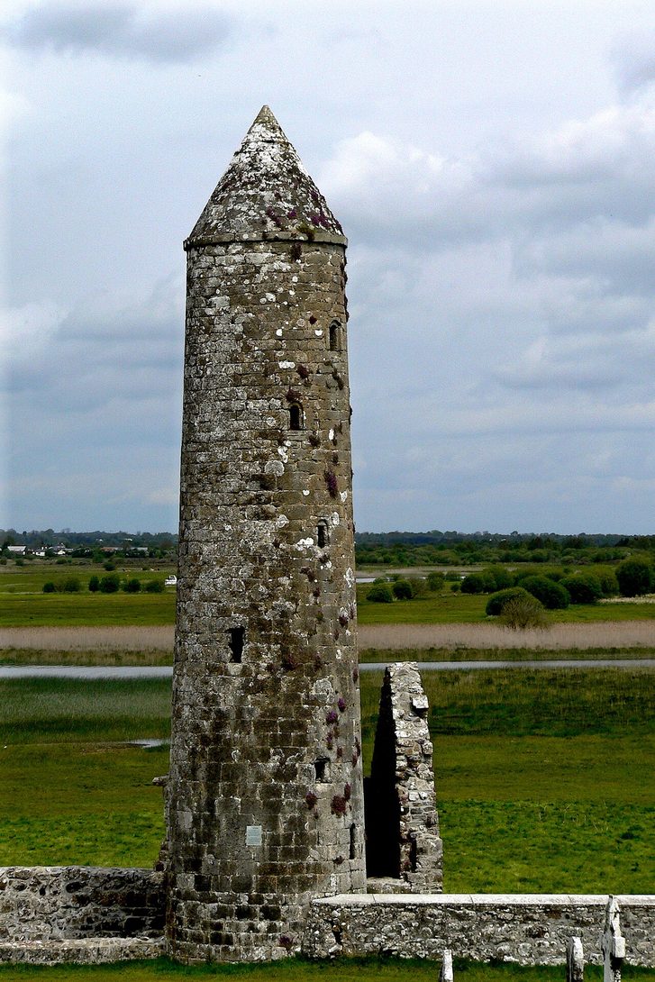 The small round tower of Temple Finghin at Clonmacnoise, with its conical stone cap, above the Shannon meadows