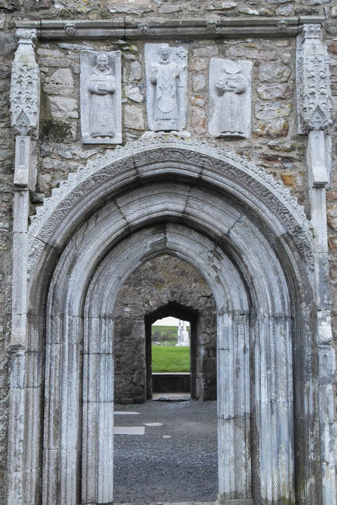 The pointed north doorway of Clonmacnoise Cathedral, framed by carved mouldings with three small saints above