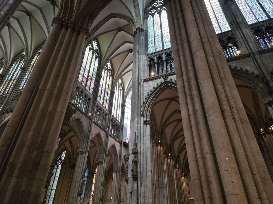 Looking up past massive clustered piers to the high windows of the nave of Cologne Cathedral