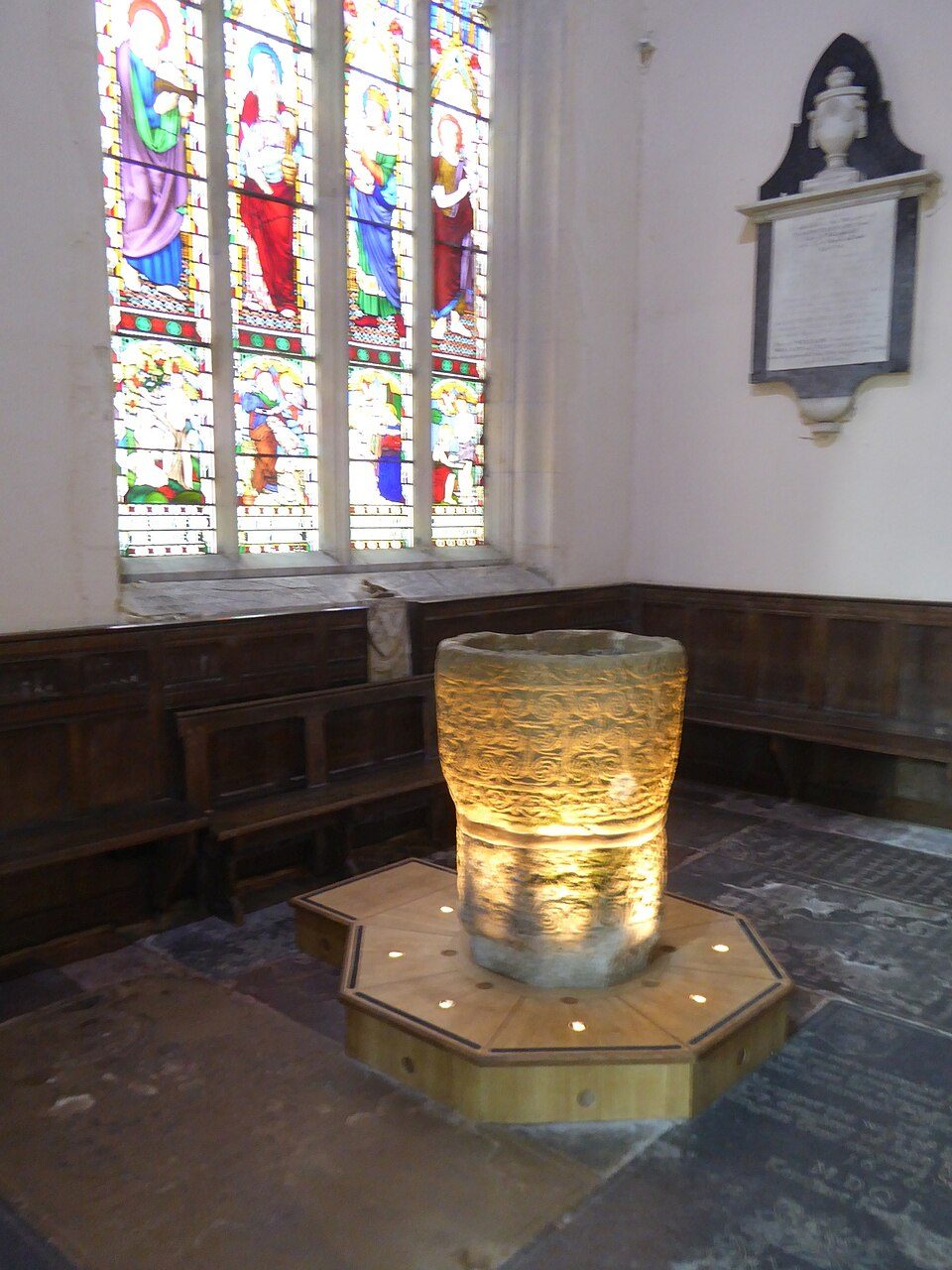 The ancient stone font at Deerhurst, a round bowl carved with bands of double spirals and vine scrolls