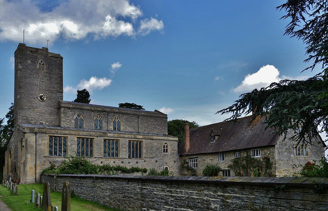 St Mary's Priory Church, Deerhurst, Gloucestershire, a tall Anglo-Saxon church with a west tower among trees and fields