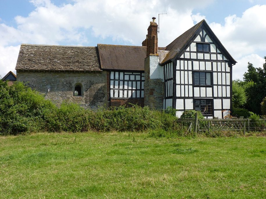 Odda's Chapel at Deerhurst, a plain stone chapel joined to the black-and-white farmhouse of Abbot's Court