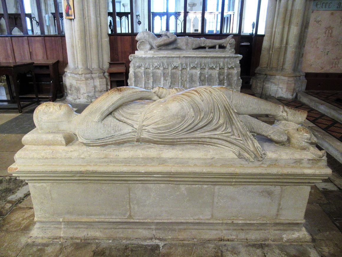 The stone effigy of a cross-legged knight in armour, twisting as he draws his sword