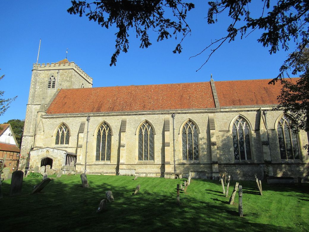 Dorchester Abbey's long stone church and square tower seen across its churchyard on a sunny day