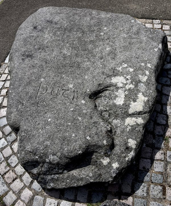 The great rough granite slab carved with the name Patric, marking the traditional grave of St Patrick at Down Cathedral