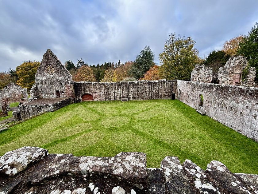 The cloister of Dryburgh Abbey, a square of lawn enclosed by ruined sandstone walls, with the gable of the south range beyond
