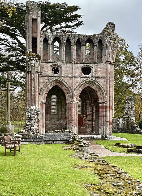 The north transept of Dryburgh Abbey, a ruined gable with tall pointed arches sheltering the burial chapels, among cedars