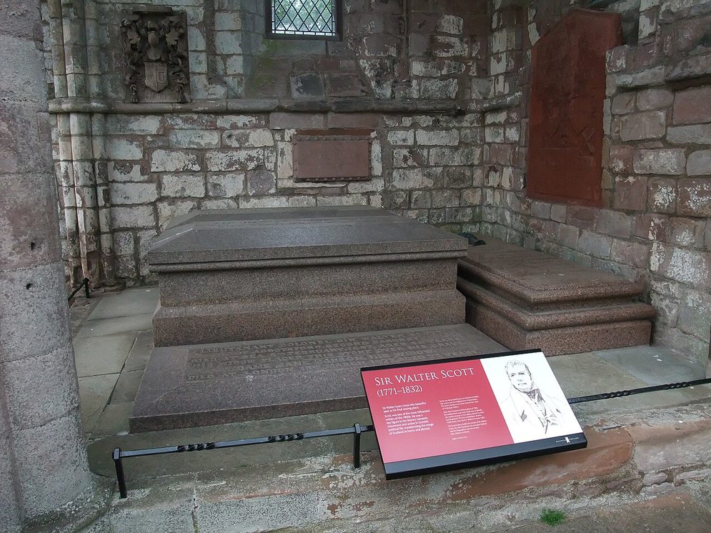 The red granite tomb of Sir Walter Scott in a chapel of the north transept of Dryburgh Abbey, with an information panel beside it