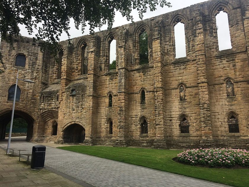 The ruined wall of Dunfermline Palace, with rows of tall windows above the glen