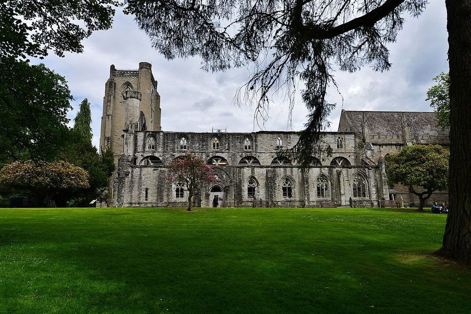Dunkeld Cathedral on the bank of the River Tay, the roofless nave and tower beside the roofed choir among trees