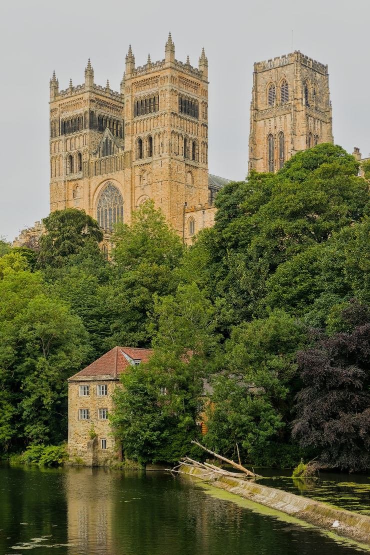The west front and towers of Durham Cathedral seen through trees from the riverbank