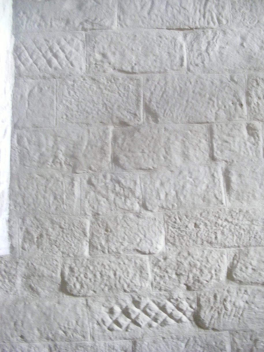 Whitewashed squared stones inside Escomb church, showing the diagonal tool marks of Roman masons