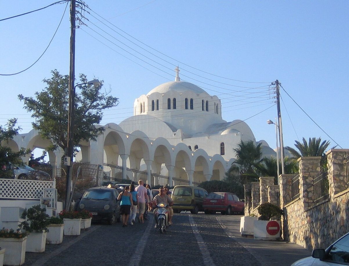 The white domed Orthodox Metropolitan Cathedral of Fira with its arcaded front, seen down a street