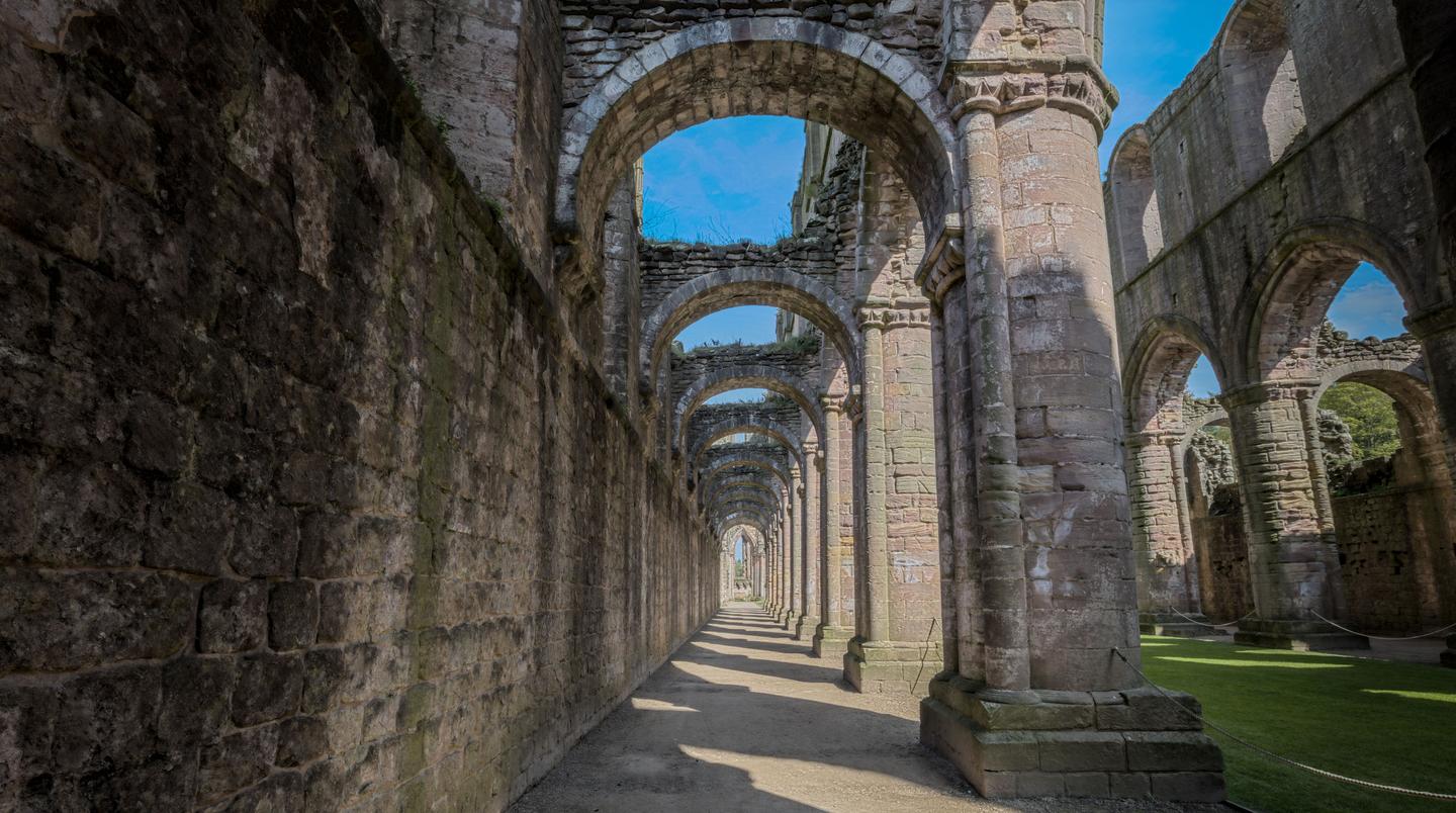 Looking along the aisle of the ruined nave of Fountains Abbey, with round pillars and open sky