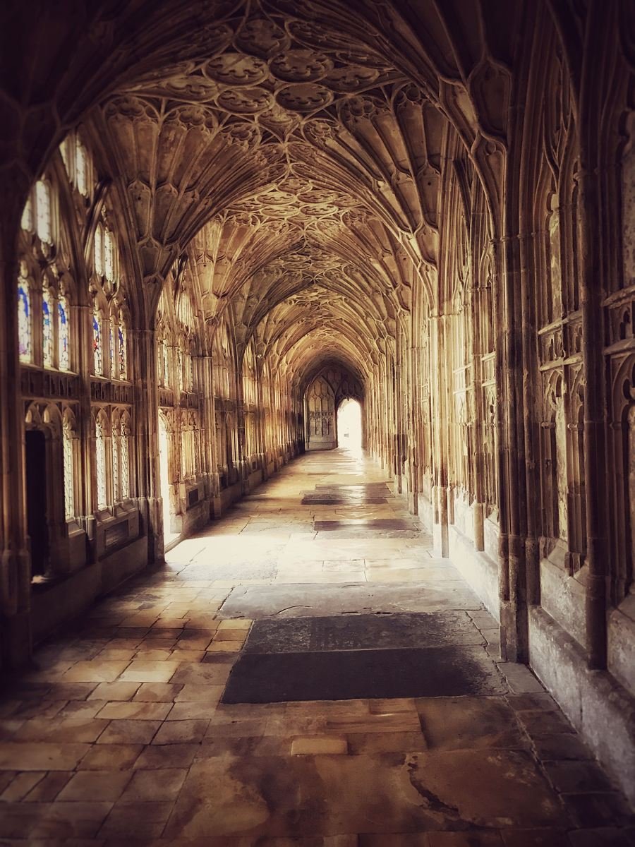 A cloister walk at Gloucester Cathedral with light through the tracery