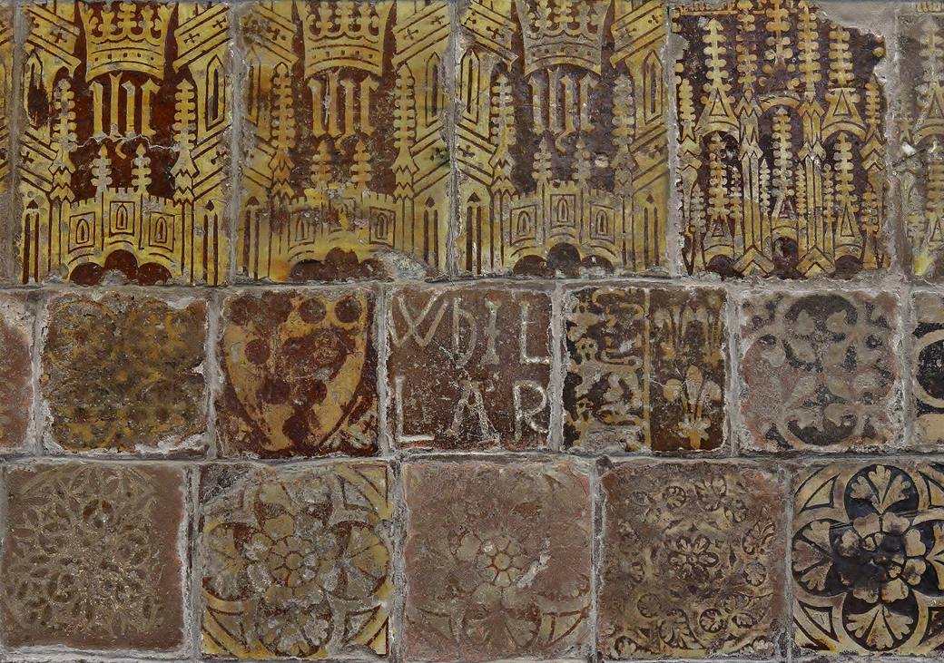 A wall of medieval glazed tiles in brown and yellow with patterns and lettering