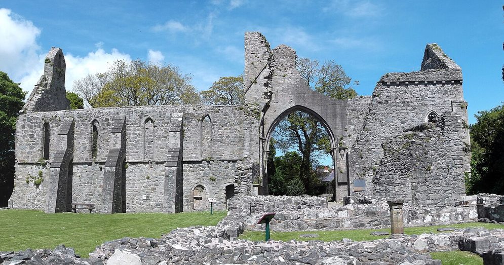 The roofless church of Grey Abbey on the Ards Peninsula, with its great arched doorway, seen across the low walls of the cloister buildings