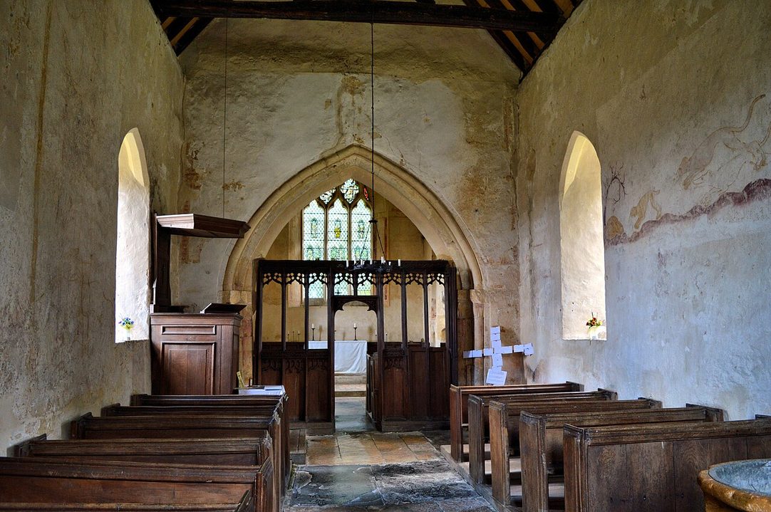 Inside the small parish church at Hailes, with old wooden pews and a carved screen in front of the chancel