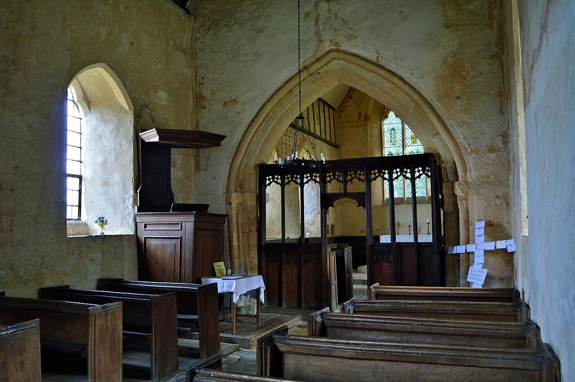 Faded medieval wall paintings with heraldic patterns and a narrow window in the chancel of Hailes church