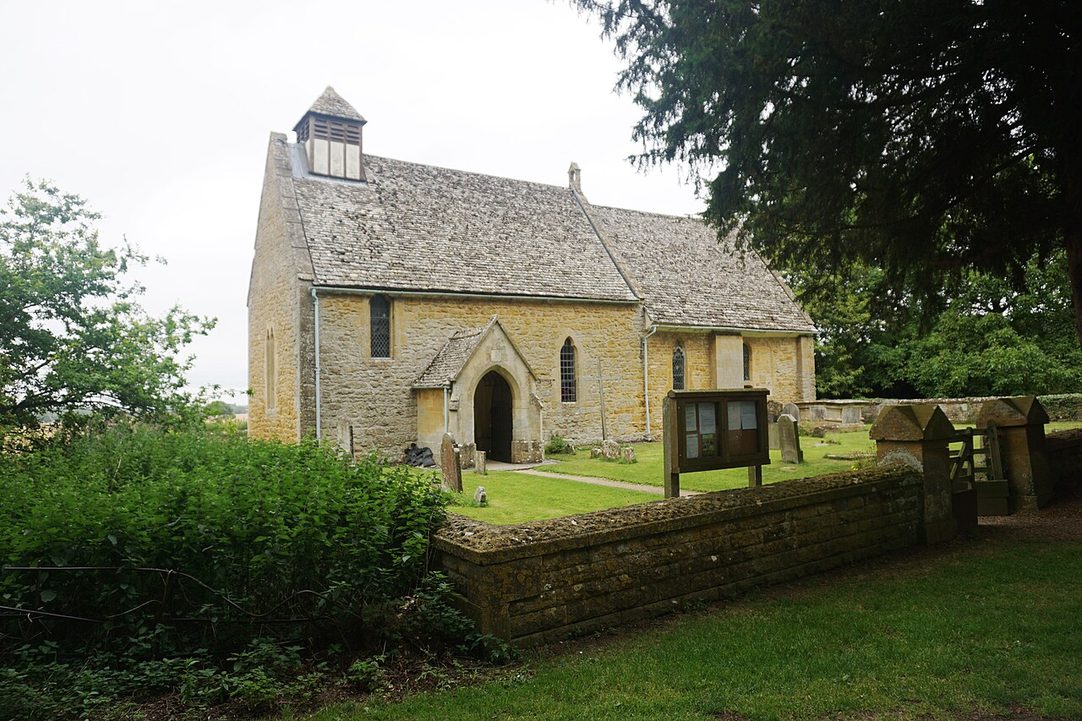 The small stone parish church at Hailes with a bellcote on its roof, in a churchyard in the Cotswold countryside