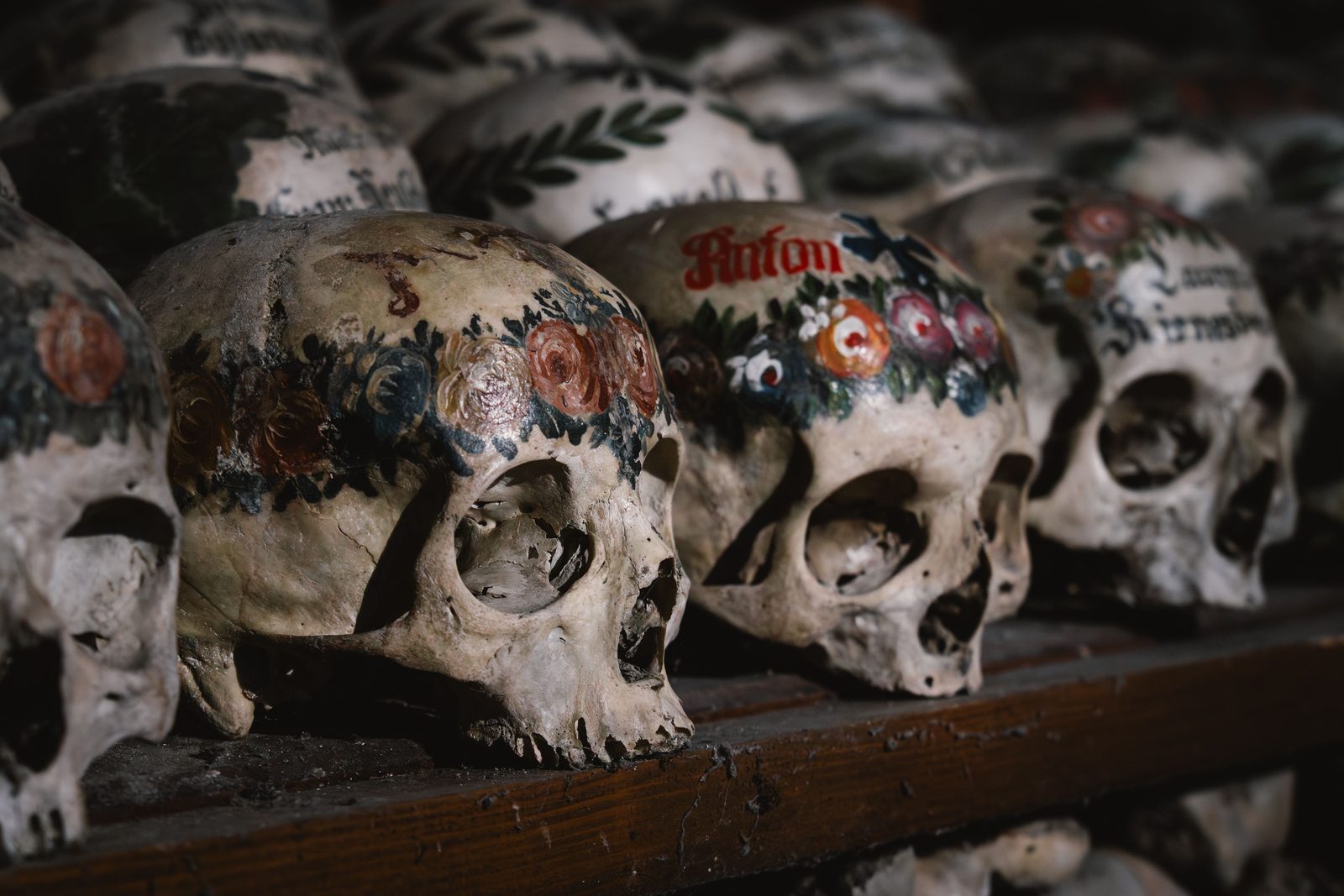 Painted skulls on a shelf in the Hallstatt charnel house, decorated with flowers and the names of the dead