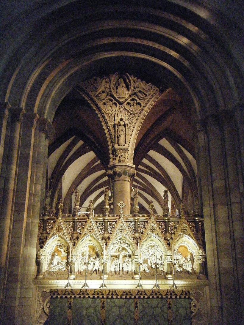 The high altar of Hereford Cathedral beneath a Norman arch, with a gilded reredos