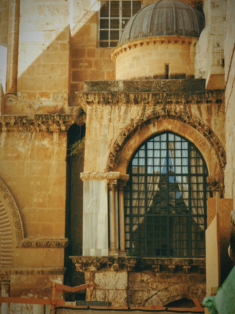 A Crusader window with a metal grille and carved stonework on the facade of the Church of the Holy Sepulchre