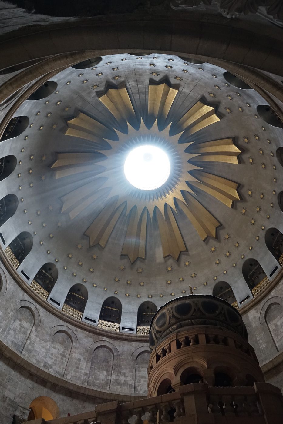 Looking up into the dome of the rotunda of the Church of the Holy Sepulchre, with a ring of gold rays around the central opening
