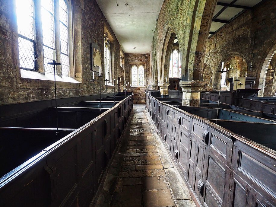 Rows of dark wooden box pews on an uneven stone floor in Holy Trinity Church, Goodramgate, York