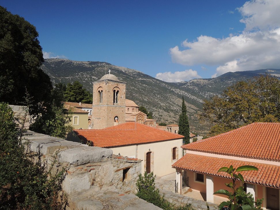 Tiled roofs of the monastery buildings at Hosios Loukas, with the bell tower and dome behind and mountains beyond
