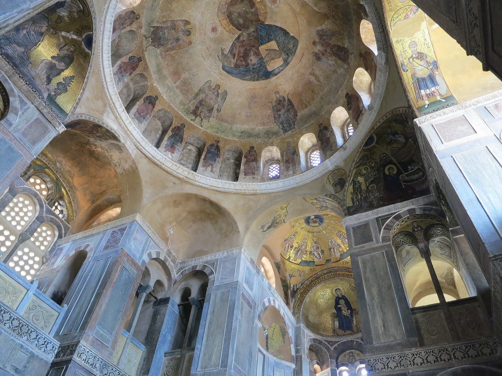The interior of the Katholikon at Hosios Loukas looking up into the dome, with marble-clad walls, galleries and mosaics on gold