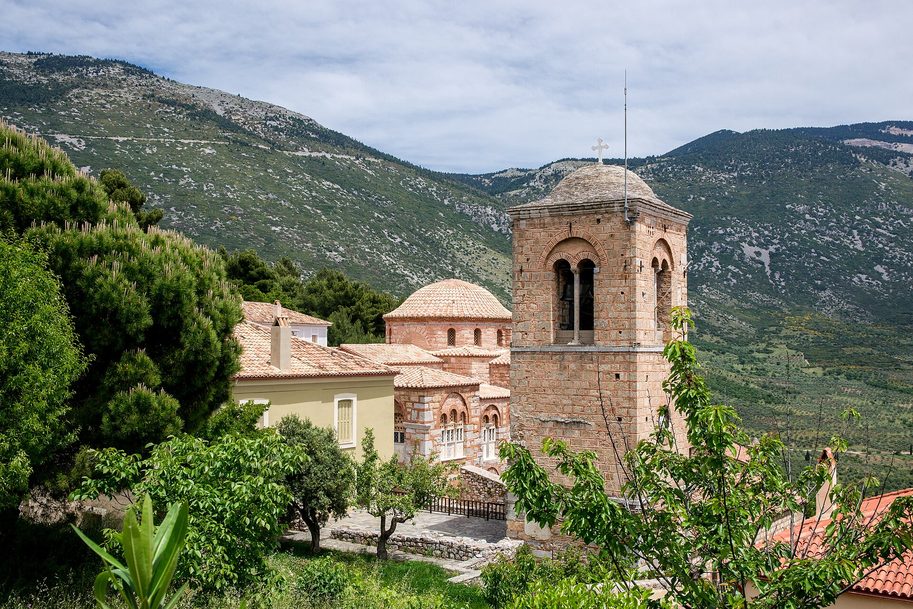 The Monastery of Hosios Loukas, with its domed churches and tall square bell tower among trees on a mountainside in central Greece