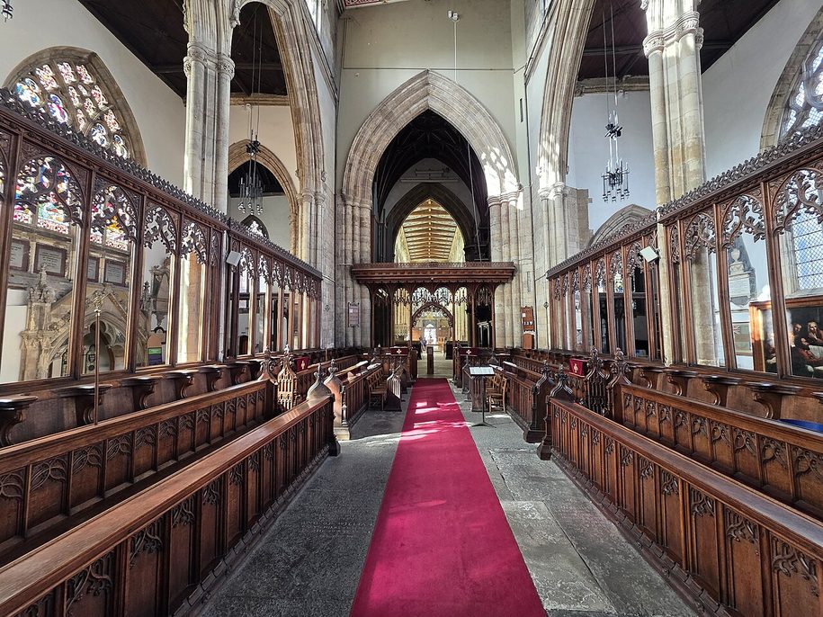 The chancel of Hull Minster with carved wooden stalls and a red carpet leading to the altar