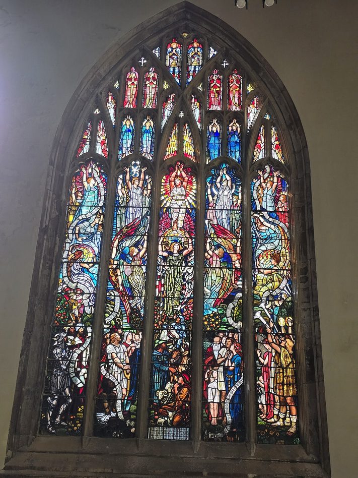 A tall stained glass window at Hull Minster filled with brightly coloured figures