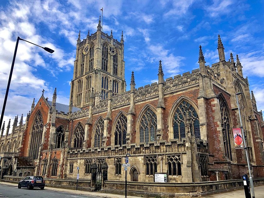 Hull Minster seen from the south, its long brick and stone body and tall central tower against a blue sky