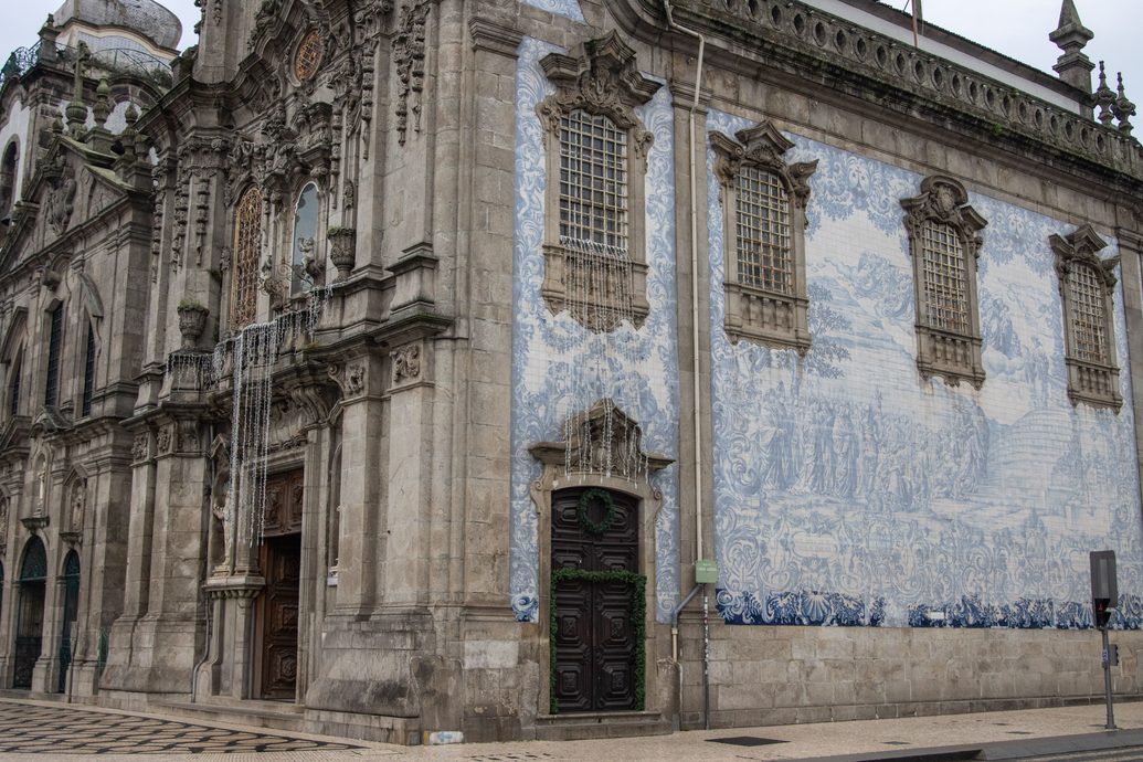 The long side wall of the Igreja do Carmo covered in a huge blue and white azulejo panel, with people walking past