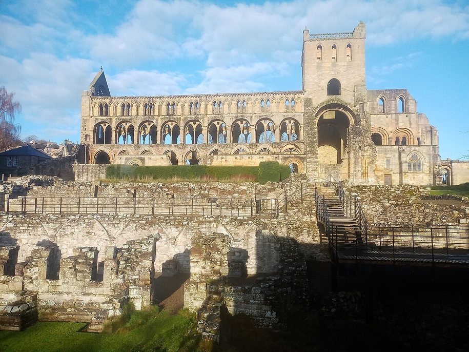 Jedburgh Abbey church seen across the low walls of the cloister and monastic buildings