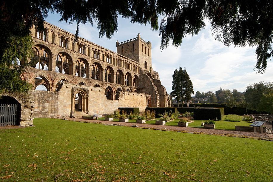 The long south side of Jedburgh Abbey church seen across a lawn and garden
