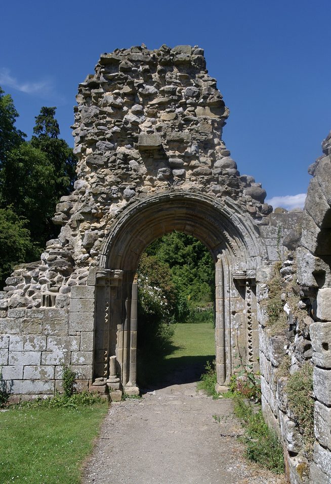 A round-arched doorway in the ruins of Jervaulx Abbey with a path running through it