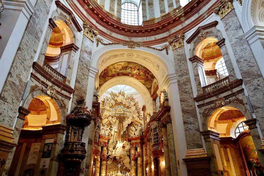 The interior of the Karlskirche in Vienna, with marble walls and arches rising to the painted dome