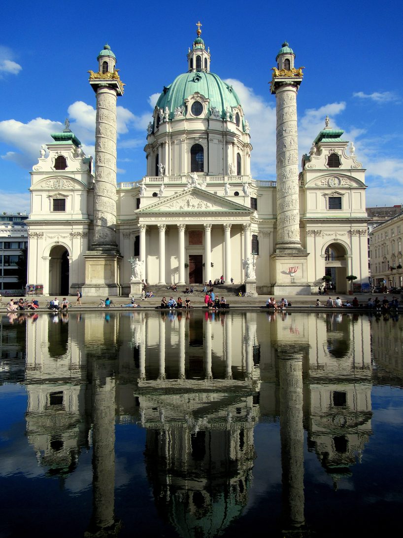 The Karlskirche and its two columns reflected in the pool in front of the church