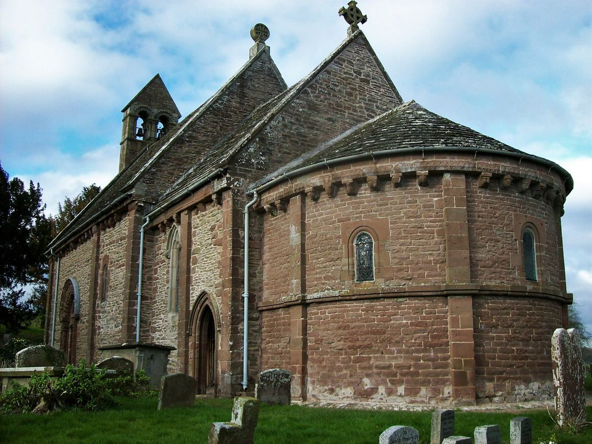 Kilpeck church, a small Norman church of red sandstone with a rounded apse, in its churchyard