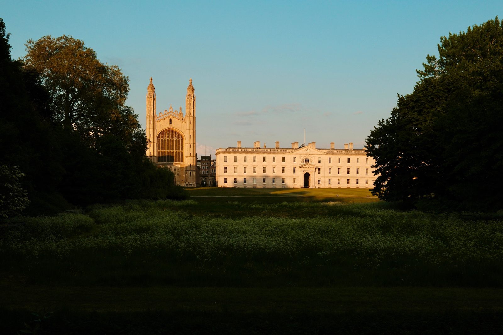 King's College Chapel and the Gibbs Building in evening sunlight seen across the meadow of the Backs