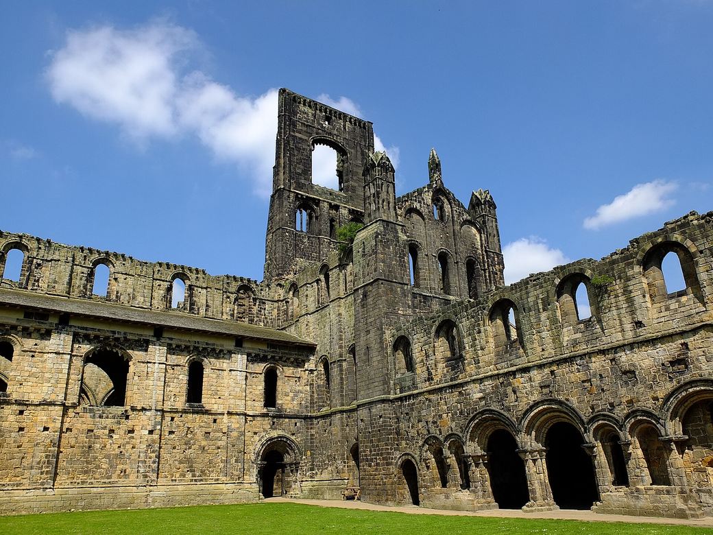 The cloister garth of Kirkstall Abbey surrounded by ruined monastic buildings