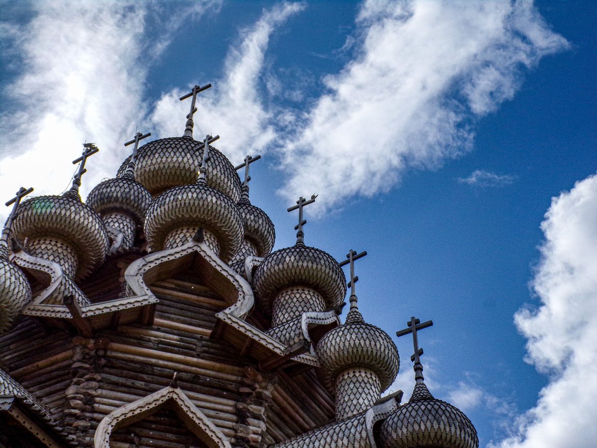 Looking up at the tiers of aspen-shingled onion domes of the Church of the Transfiguration at Kizhi against a blue sky