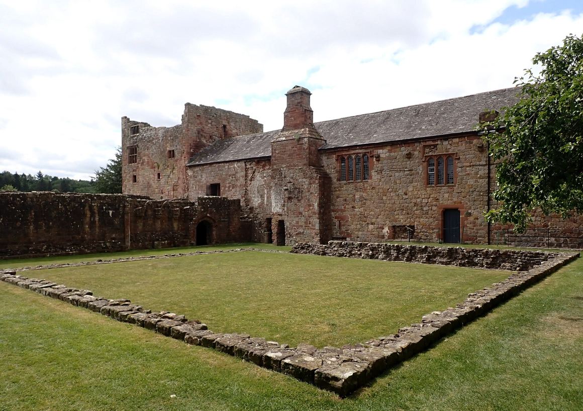 The grassed cloister of Lanercost Priory with the Dacre Tower and the remains of the monastic buildings