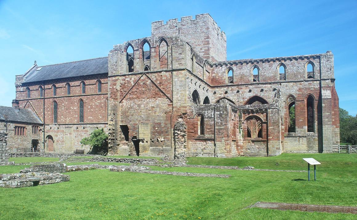 Lanercost Priory: the red sandstone church with its west front, beside the roofless ruins of the priory