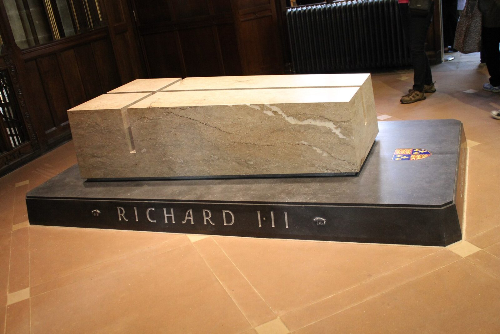 The tomb of Richard III, a pale stone block incised with a cross on a dark plinth carved with his name