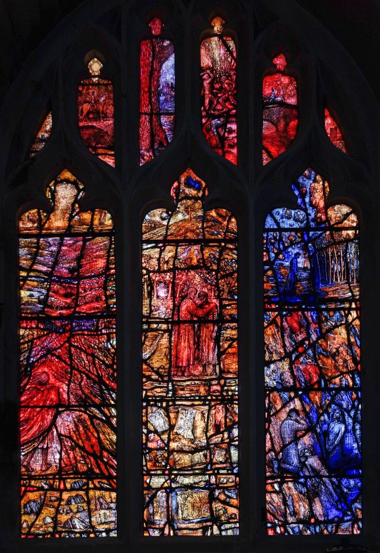 A brightly coloured three-light stained-glass window in reds and blues